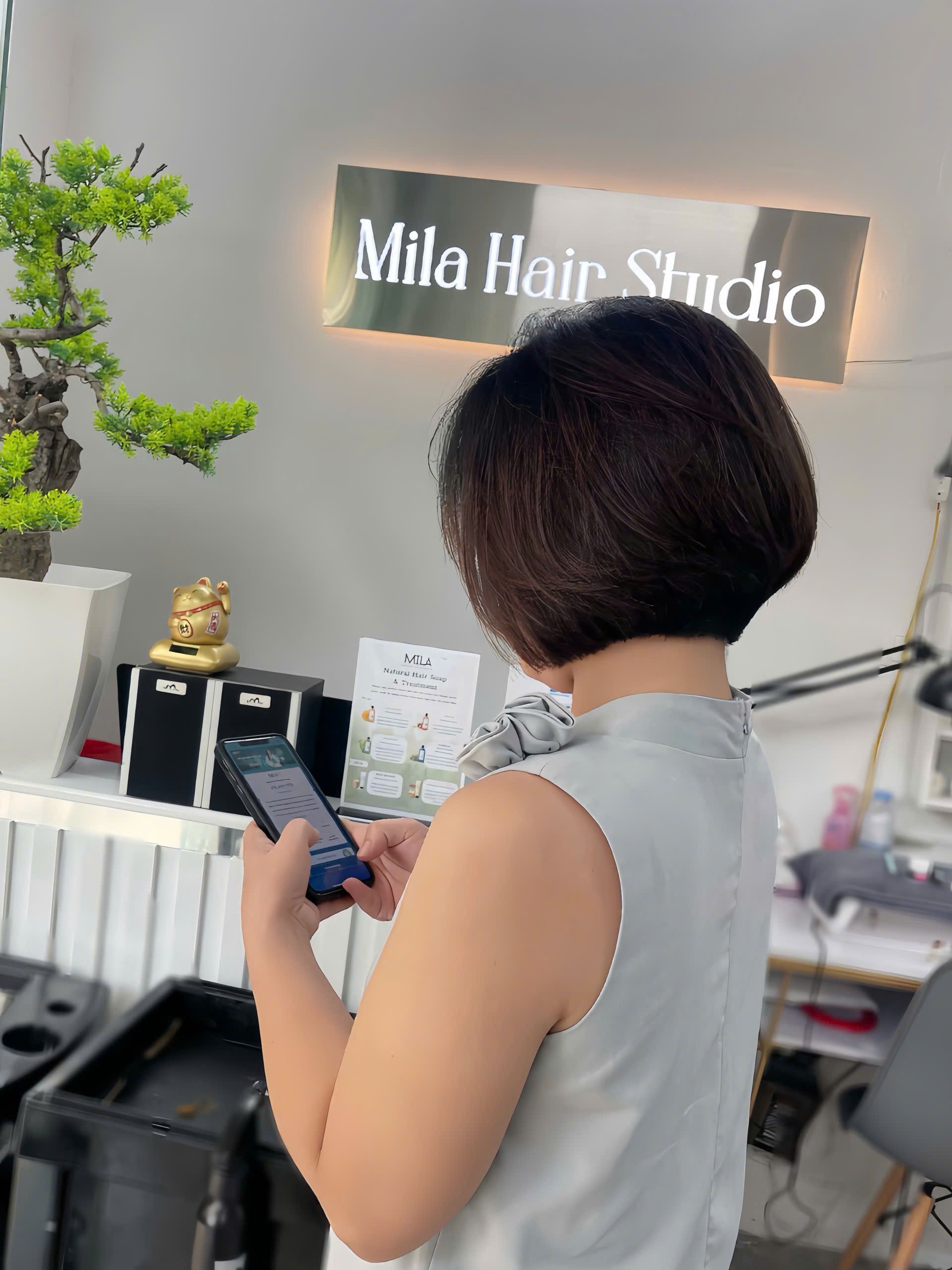 Khách tóc bob ngắn đứng trước biển hiệu Mila Hair Studio