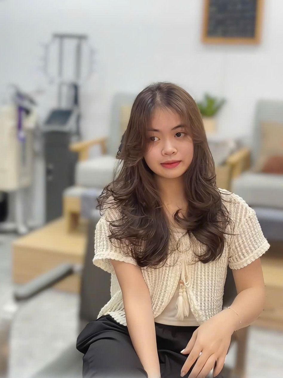 Khách nữ tóc ngang vai uốn cụp sóng nhẹ màu nâu, ngồi tại salon MiLa