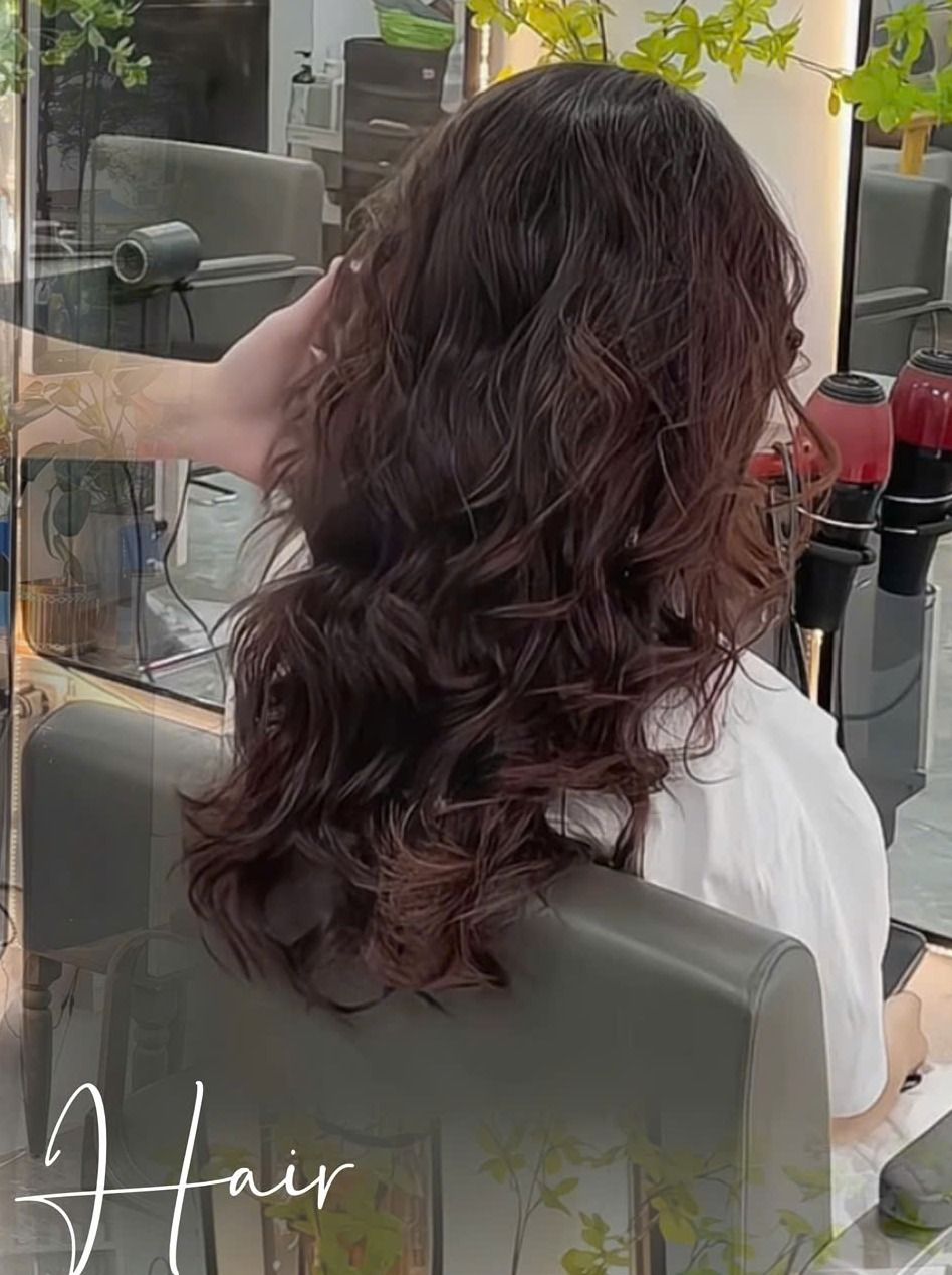Tóc dài uốn xoăn lơi màu nâu đỏ, nhìn từ phía sau tại salon MiLa